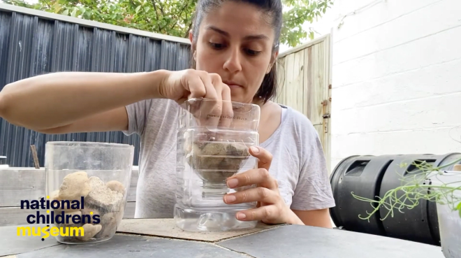 A woman placing stones into a homemade plastic planter.