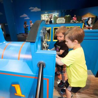 Two little boys playing in the cab of Thomas the Train
