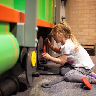 Little girl fixing a wobbly wheel on a life-sized Percy the train