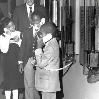 An archival, black and white photo of children on telephones