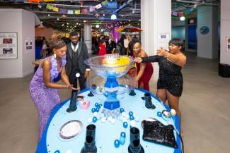 People in formal wear playing at the Placita Mágica exhibit