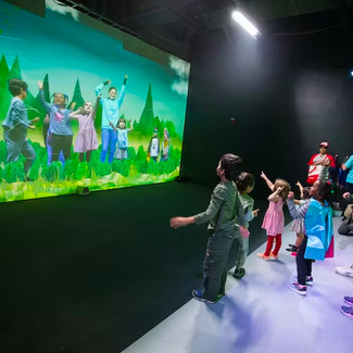 a group of kids seeing themselves on the weather worlds green screen