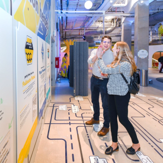 Two adults high five while standing on a decal floor maze.