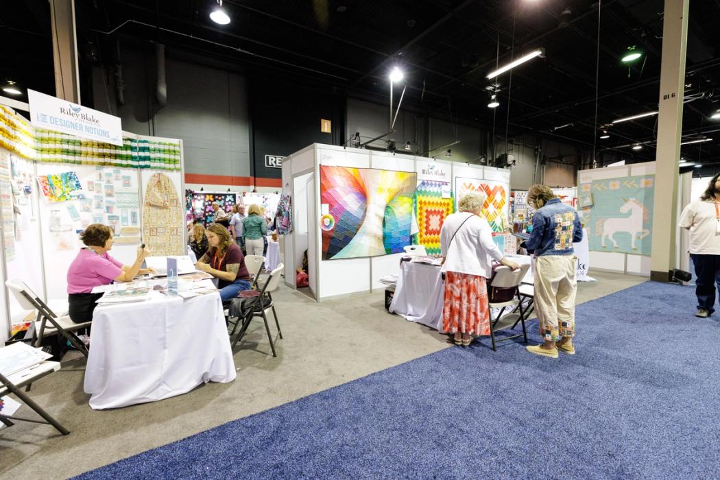 Trade show attendees in discussion with exhibitors on the show floor. 