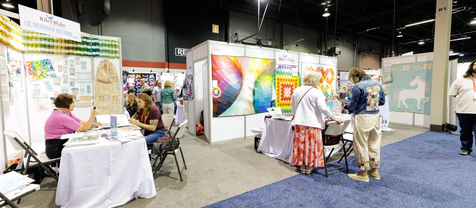 Trade show attendees in discussion with exhibitors on the show floor.
