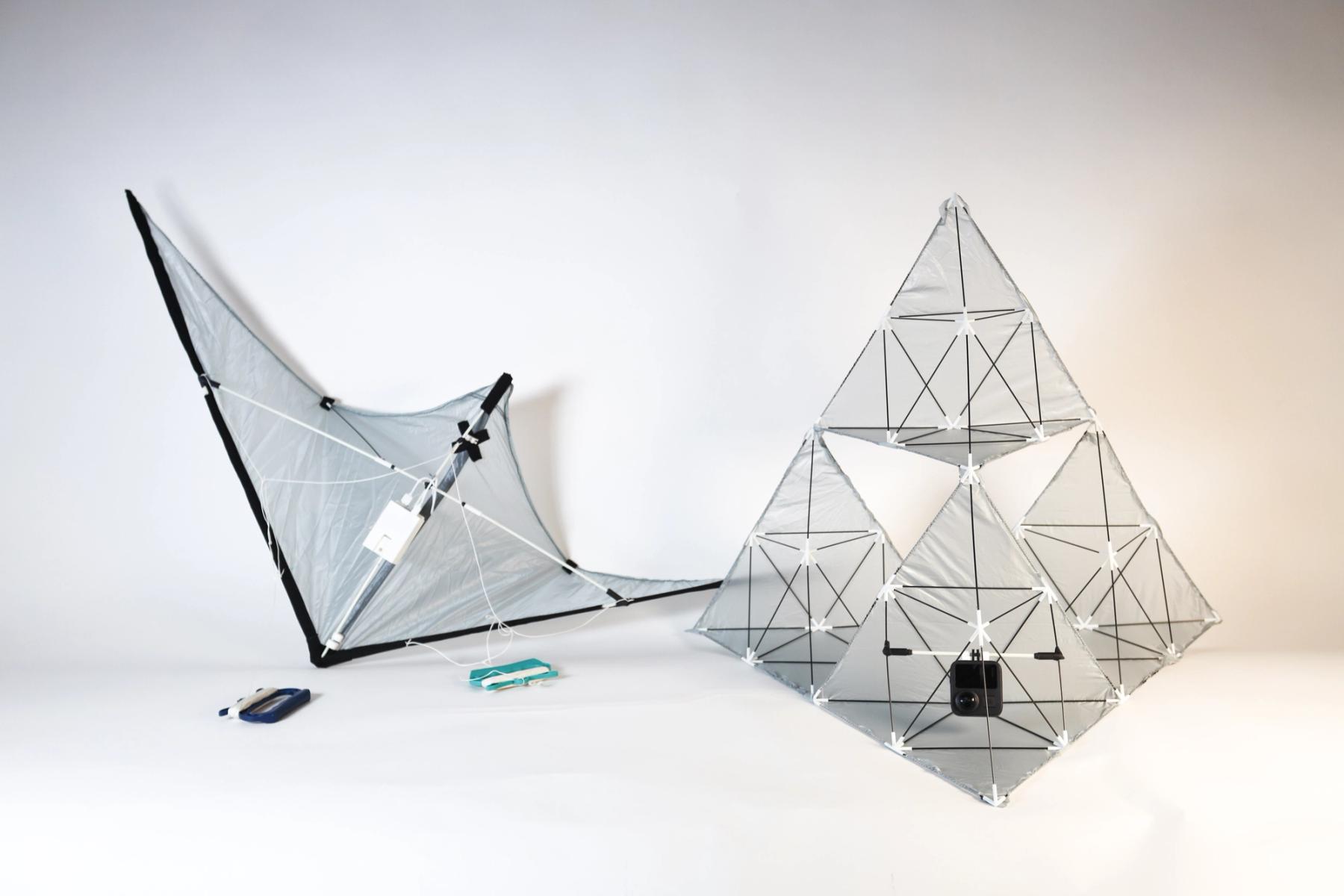 Two experimental lightweight structures made from translucent fabric stretched over geometric frames, including a modular pyramid-shaped form with an attached camera.
