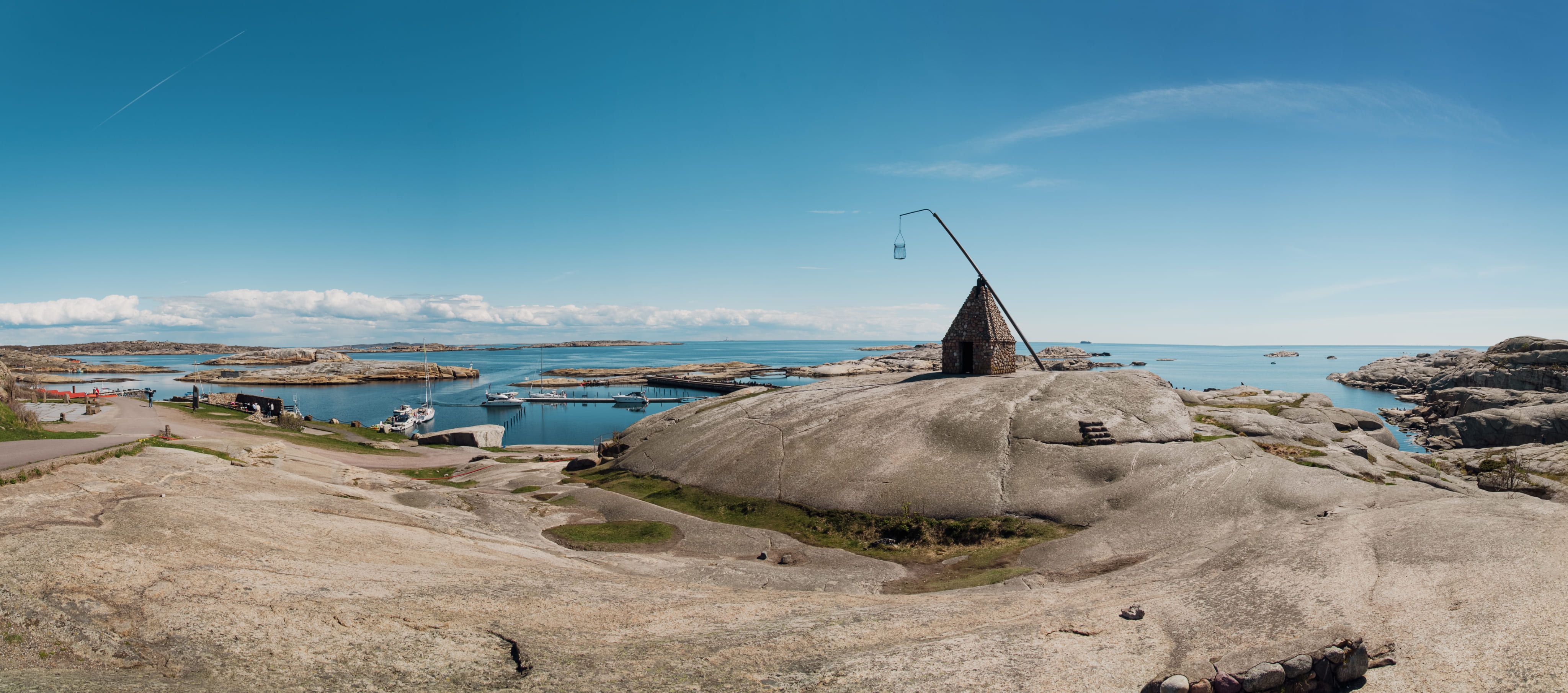 Svaberg ved Verdens Ende på Tjøme med vippefyret og båthavn i bakgrunnen