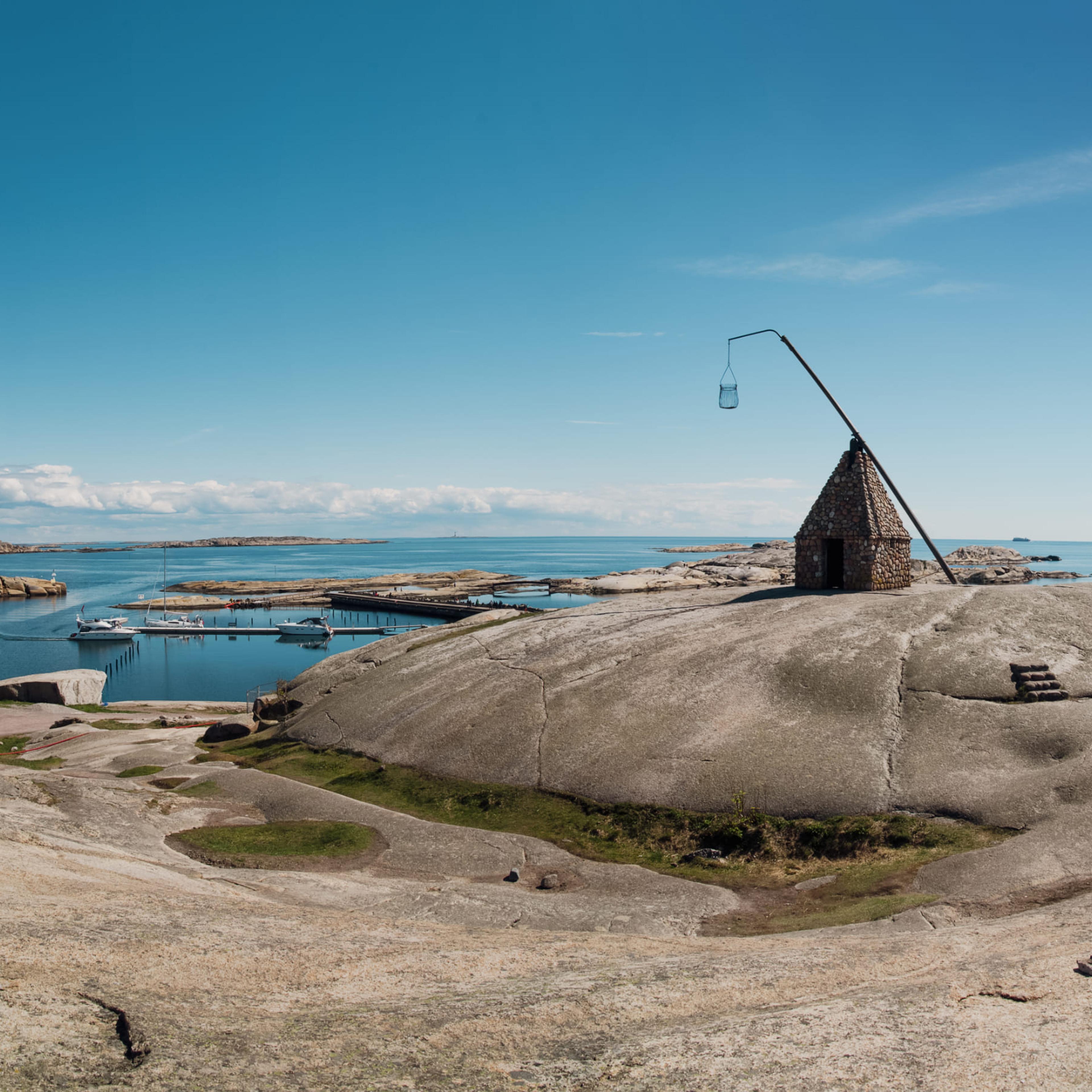 Svaberg ved Verdens Ende på Tjøme med vippefyret og båthavn i bakgrunnen