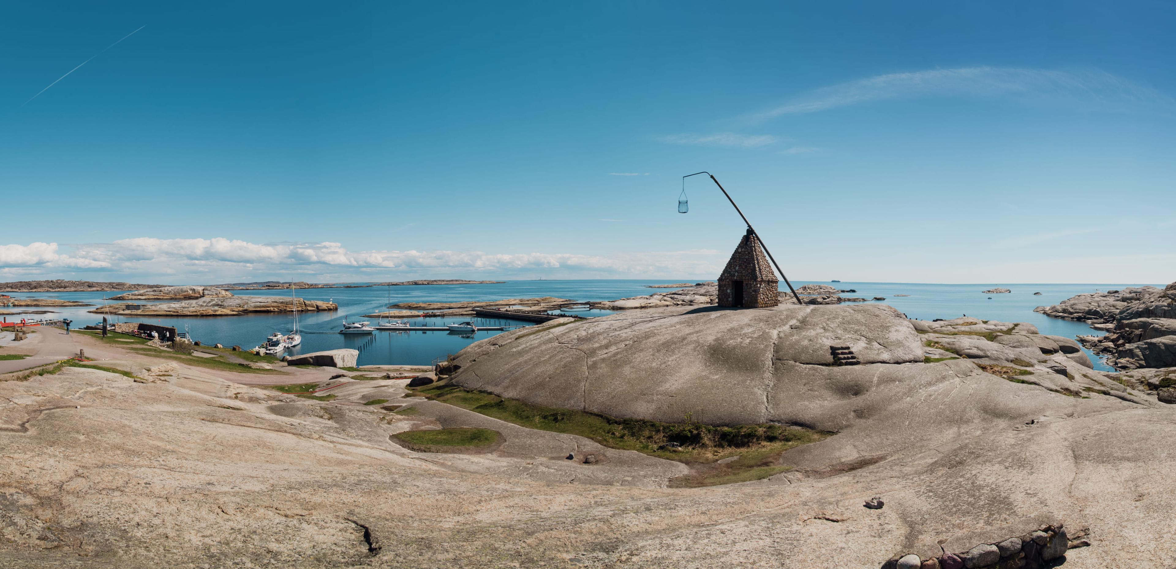 Svaberg ved Verdens Ende på Tjøme med vippefyret og båthavn i bakgrunnen