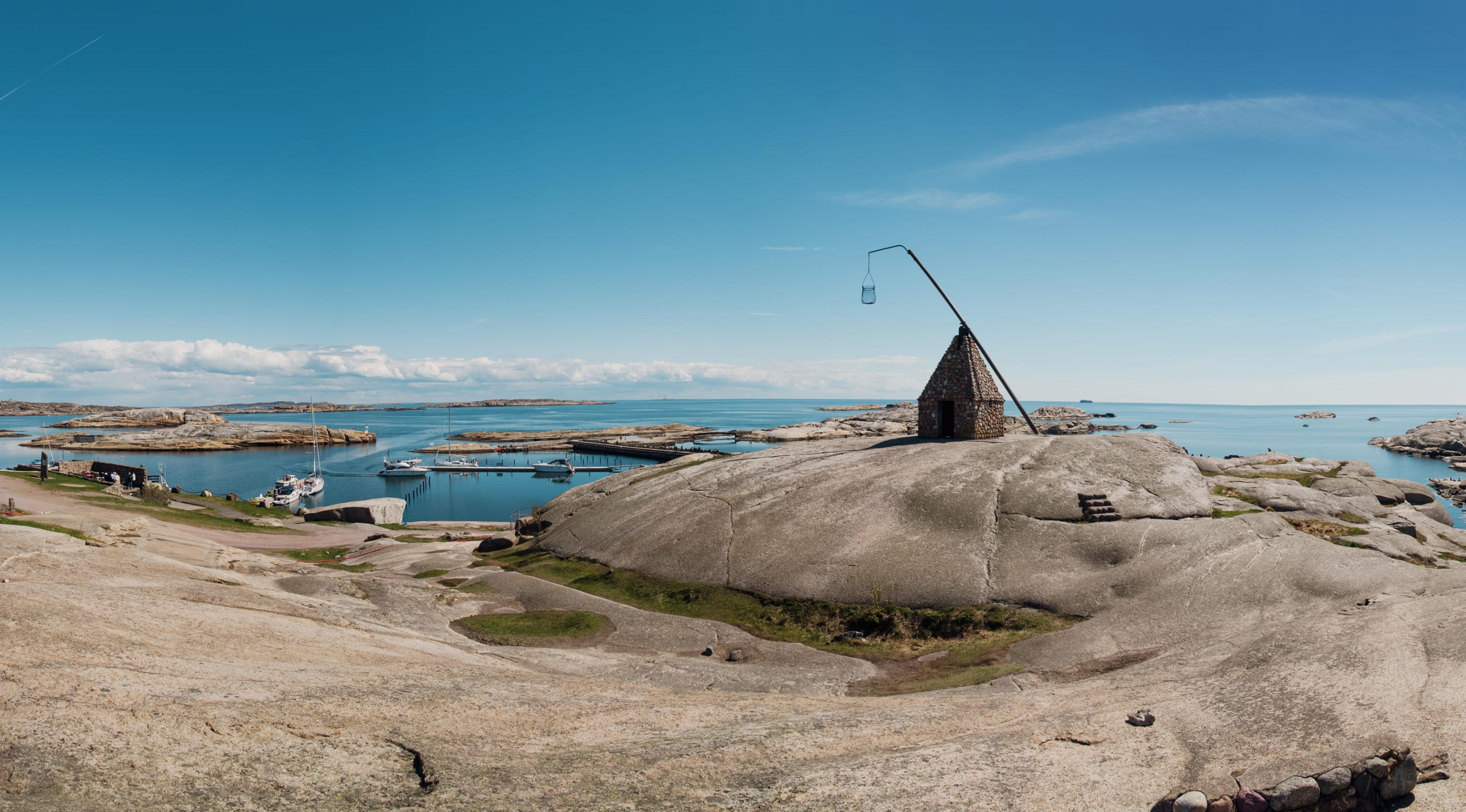 Svaberg ved Verdens Ende på Tjøme med vippefyret og båthavn i bakgrunnen