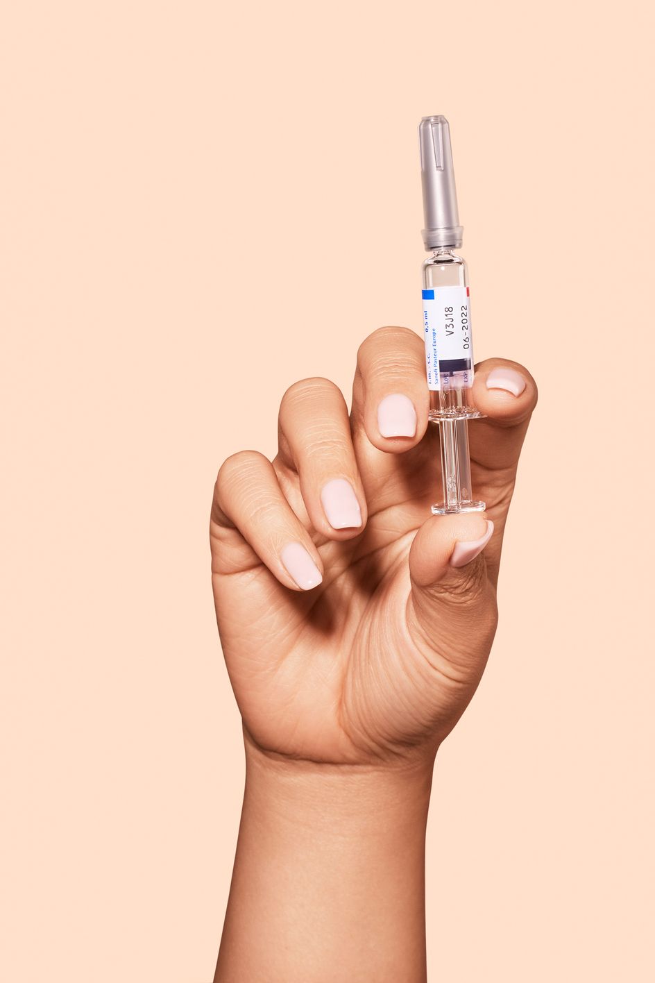 Vaksine i en hånd på beige bakgrunn