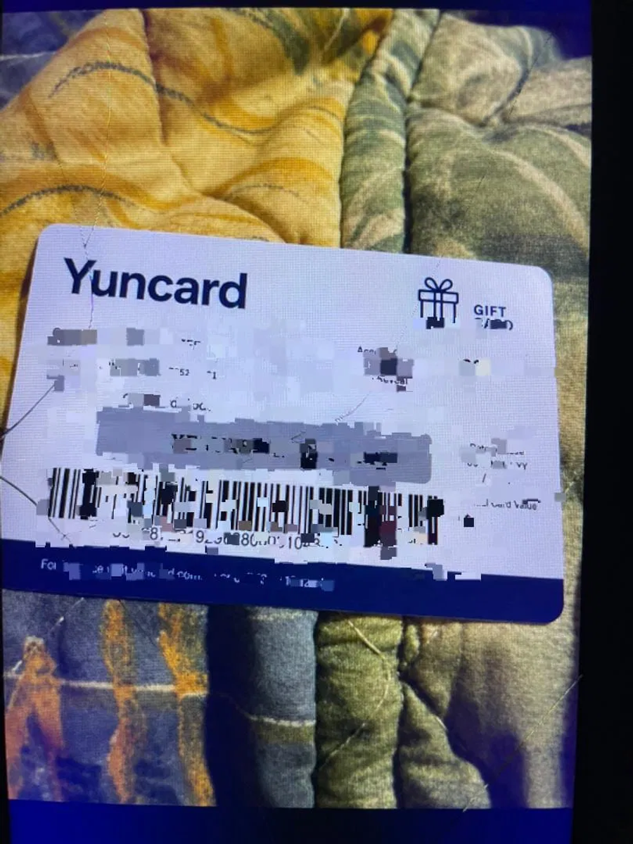 photo of a suspected AI-generated Yuncard gift card with distorted text and blurred barcode