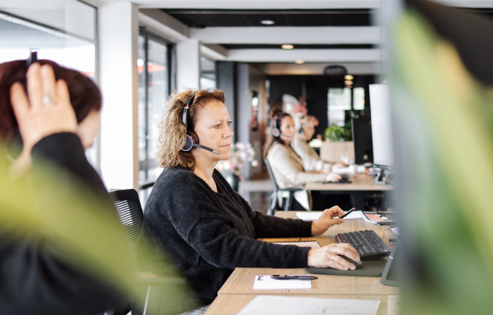 Vrouw met headset werkt achter de computer in een kantoor