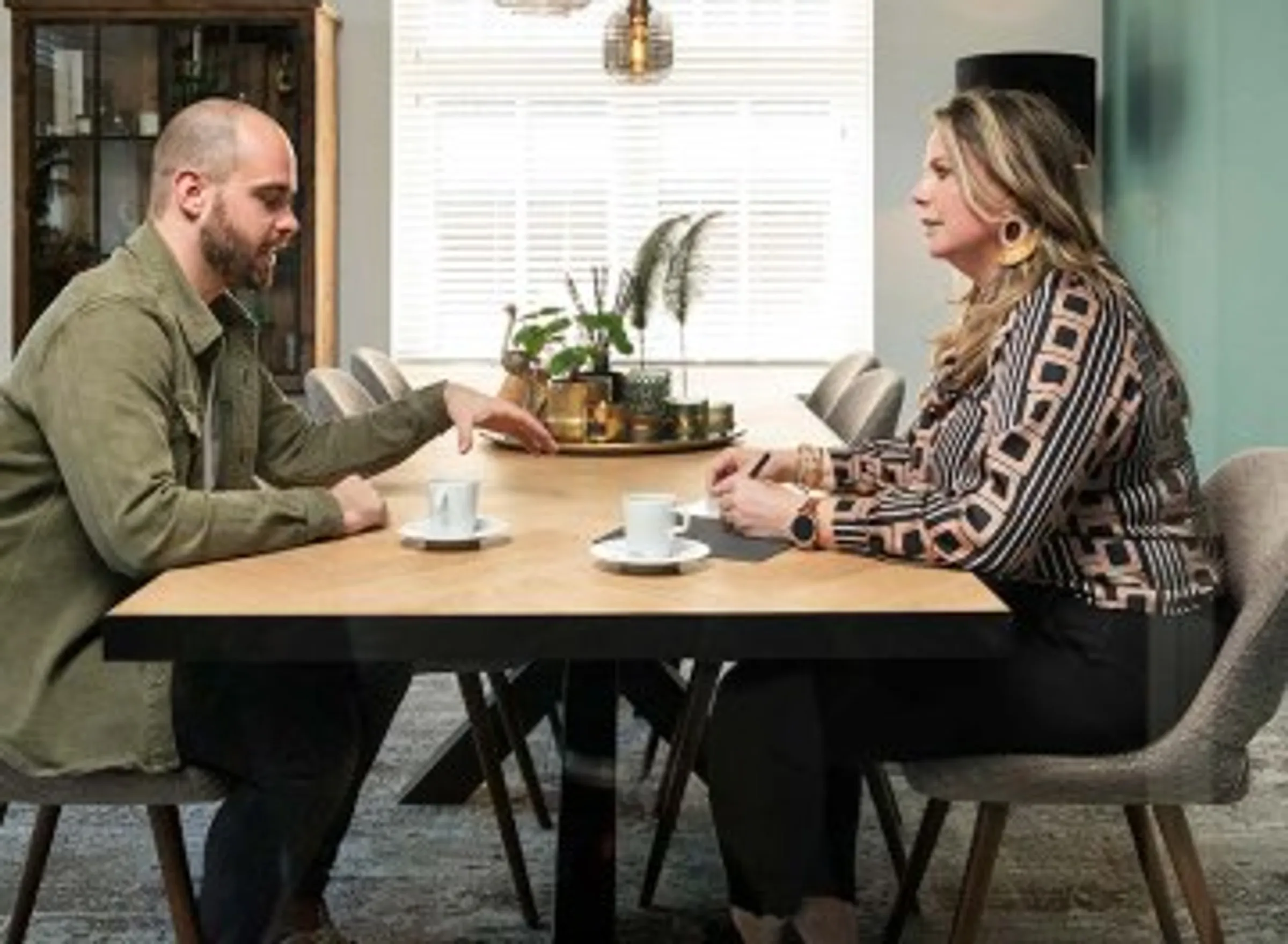 Twee vrouwen in gesprek aan een houten vergadertafel in een modern kantoor