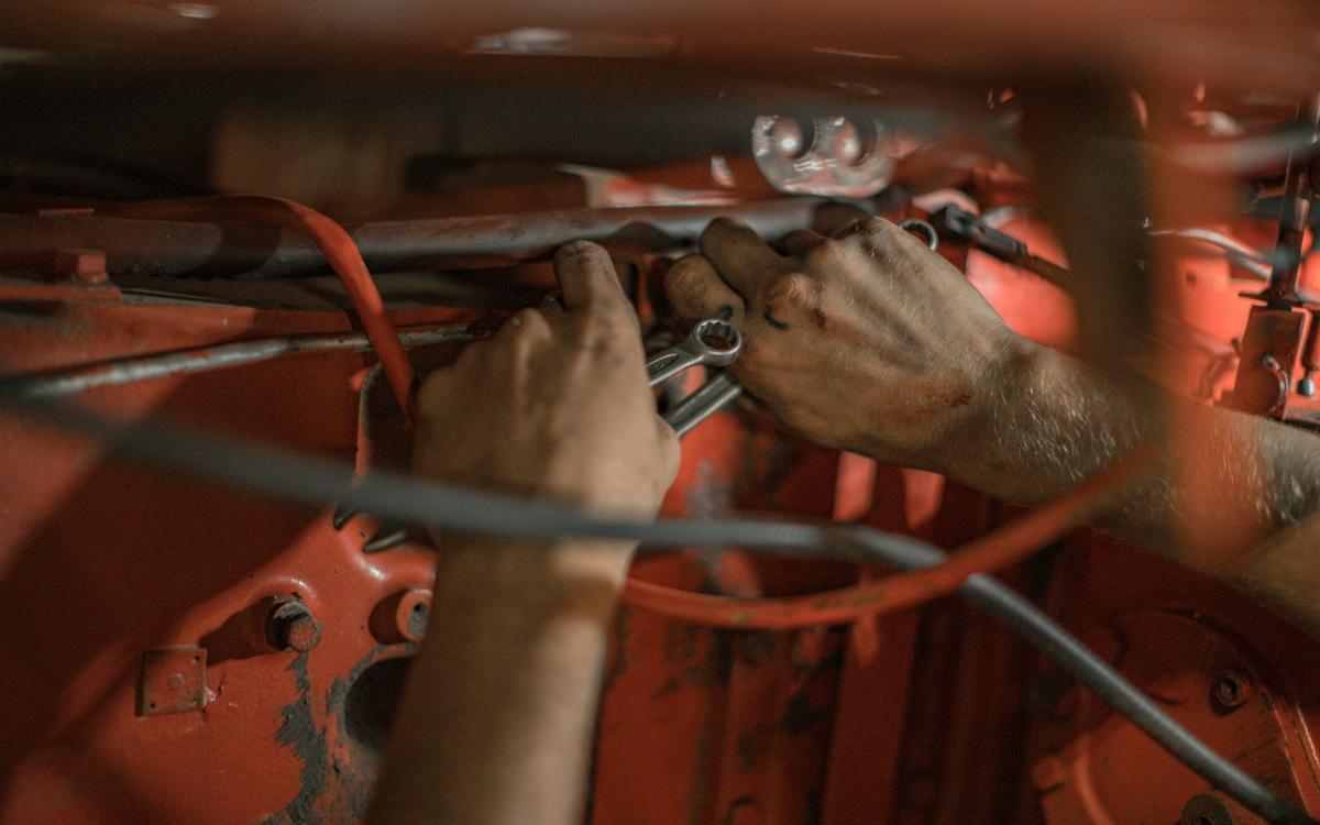 Hände arbeiten mit einem Schlüssel am Motor eines Autos