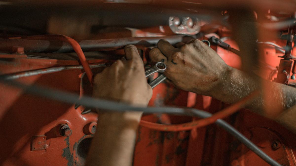 Mani al lavoro sul motore di un'auto con una chiave