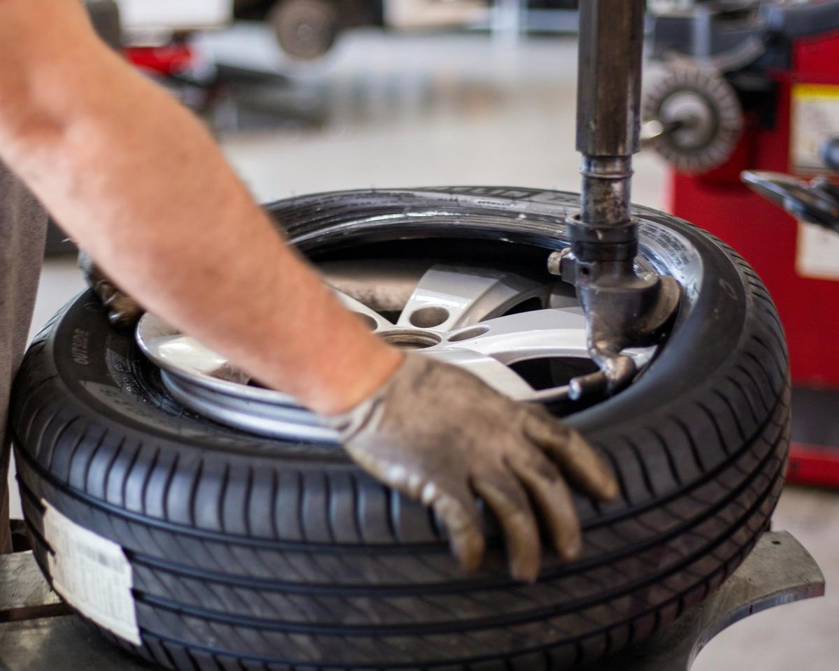 Mechaniker montiert einen Reifen auf der Montiermaschine in der Werkstatt