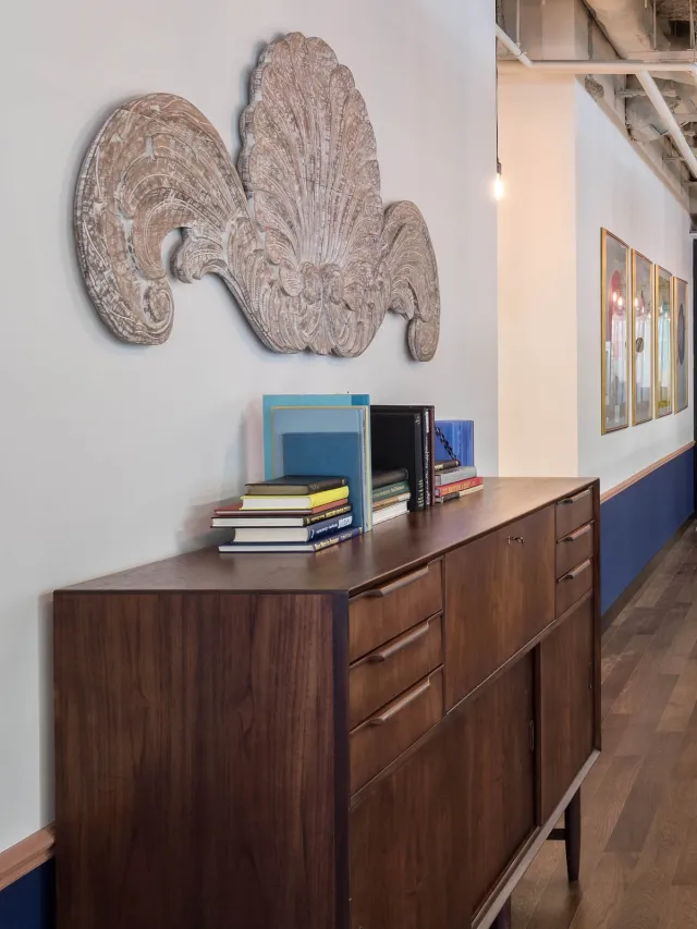 A vintage wooden credenza with books in a hallway