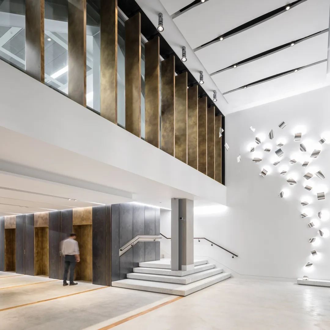 photos of reception of office building with sculpture and elevators in bronze