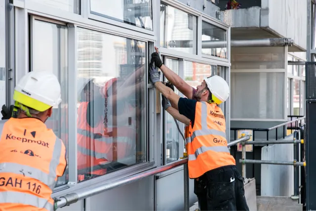 Builders working on facade dressed in orange