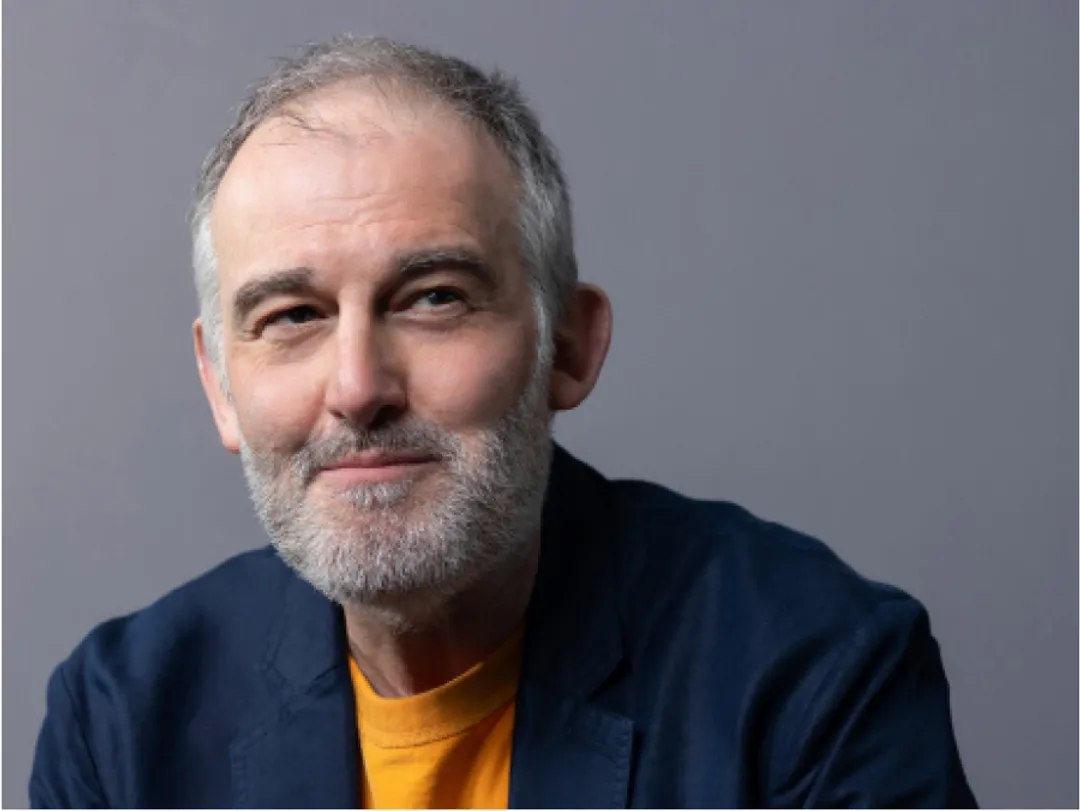 Portrait of person in dark blue jacket with orange top