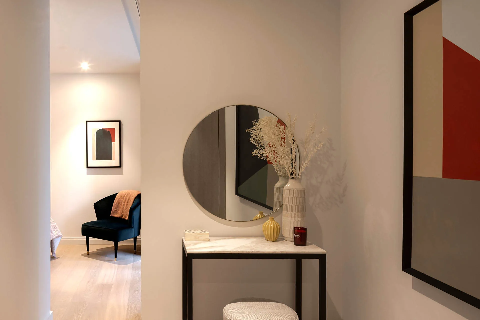 A small marble dressing table in front of a round mirror, armchair in background