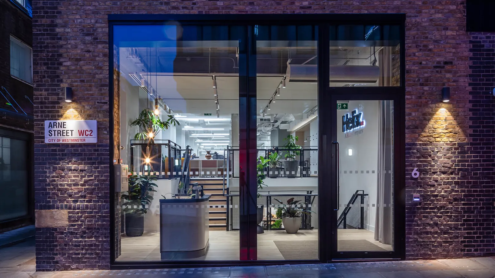 Exterior view of shop front at dusk with interior lights on