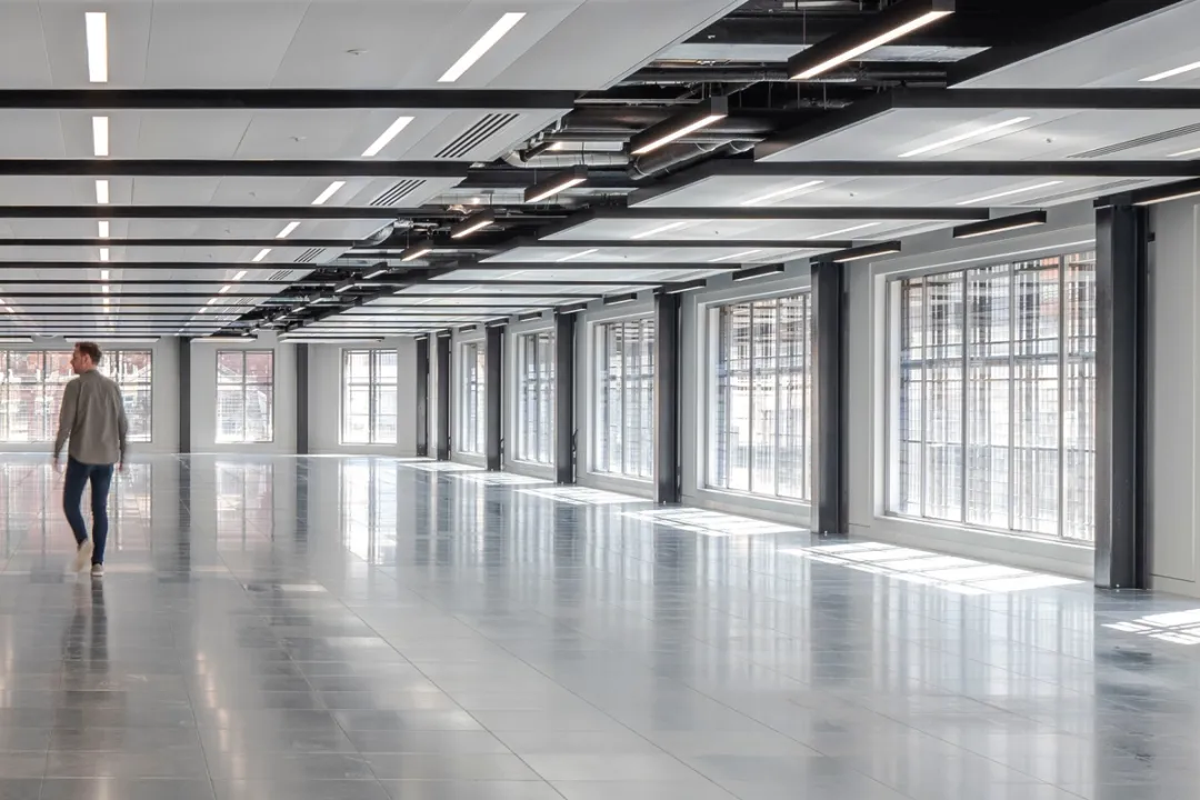 view of office empty space with person walking and windows