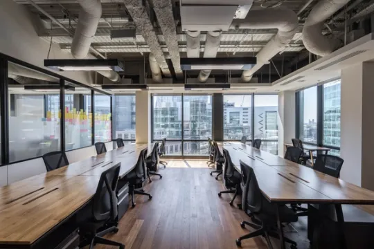 Glass walled office with two long hot desks and ergonomic chairs