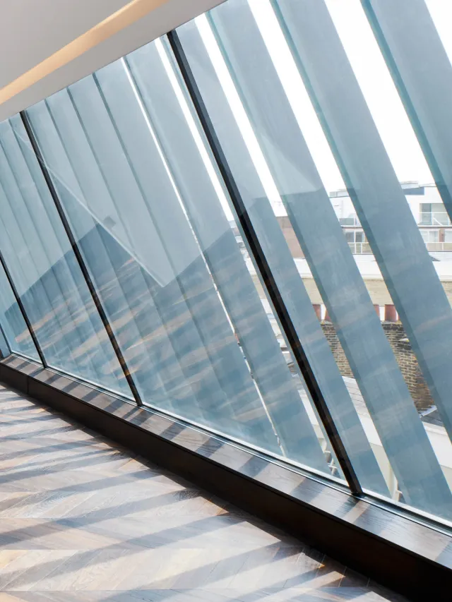 Internal side view of mansard fins through window casting striped shadows on a dark brown floor