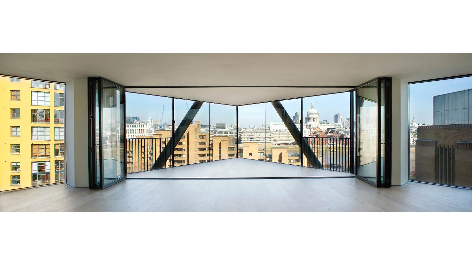 Inside an empty apartment looking out of floor to ceiling windows showing South Bank, St Paul's Cathedral and Tate Modern