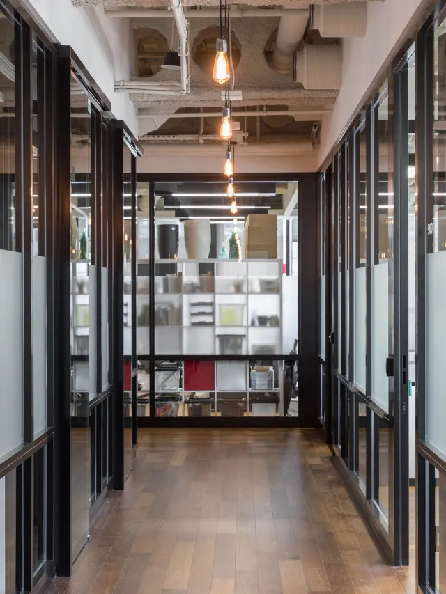 A hallway with glass screen walls on both sides, decorative shelves at the end