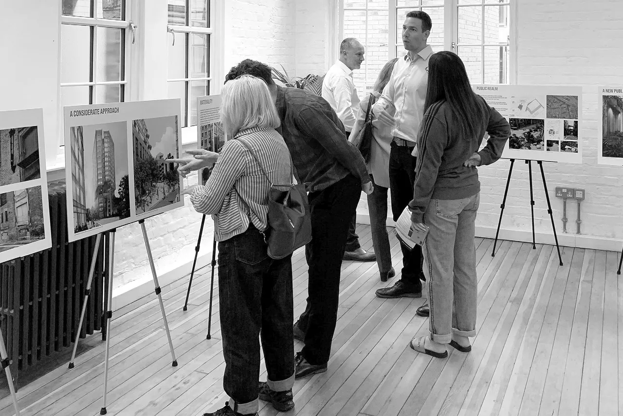 People looking at exhibited architectural plans in room