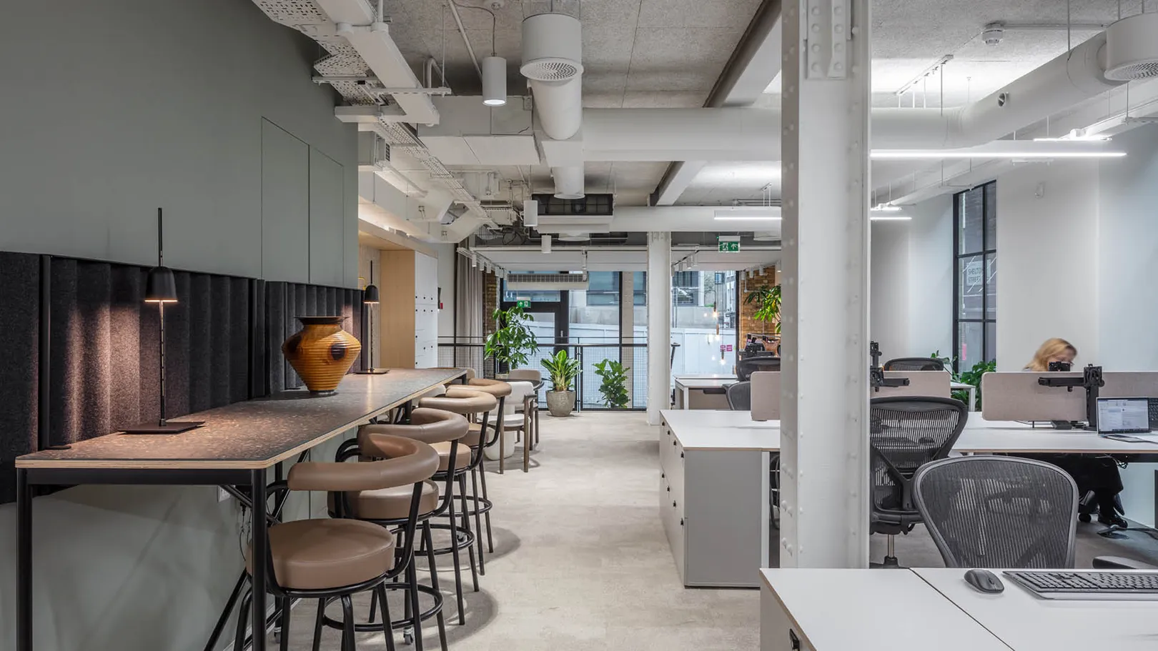 An open plan office floor with grey furniture and bar seating on left