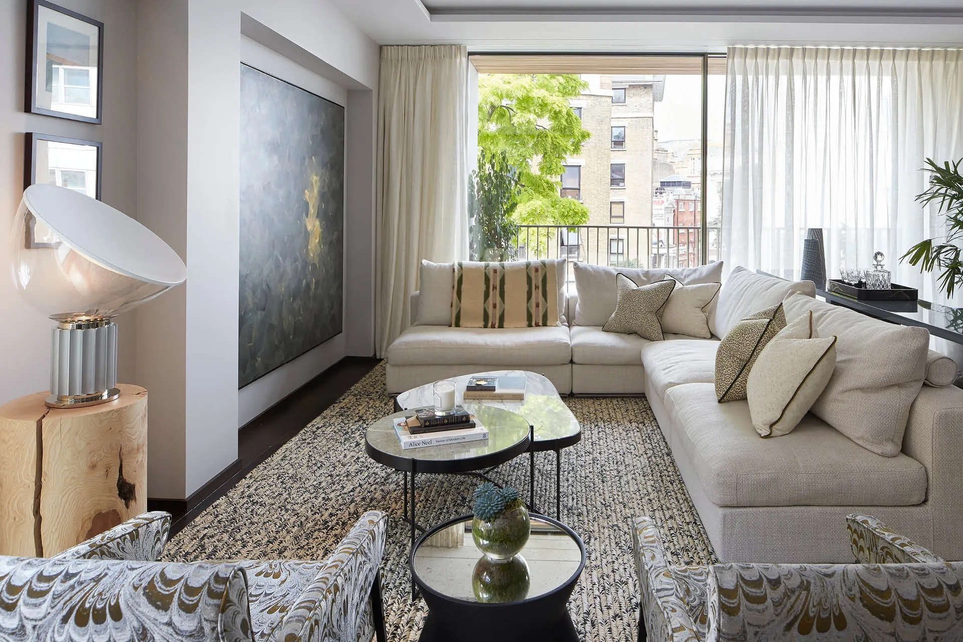 A luxury sofa and armchairs with artwork and a balcony beyond