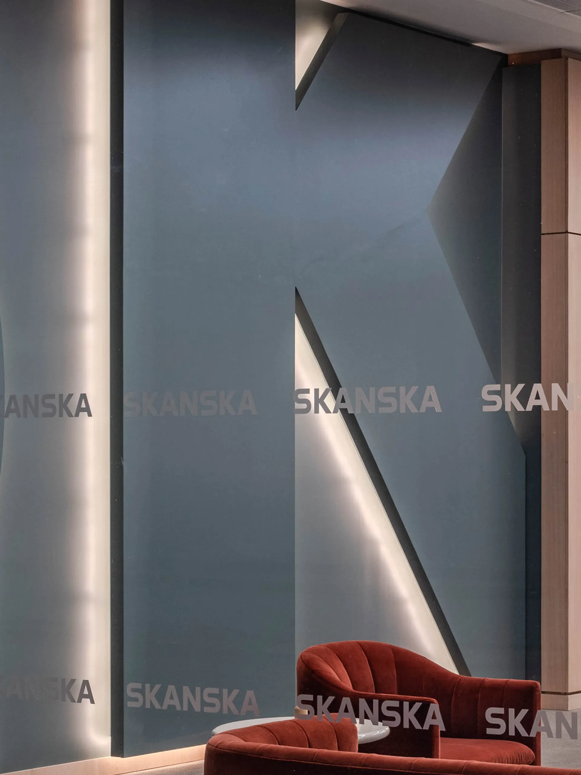 A backlit letter K with orange armchairs in front