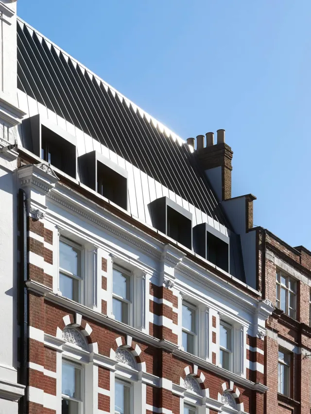 Exterior view of triple height silver mansard roof with fin cut-outs above red brick building