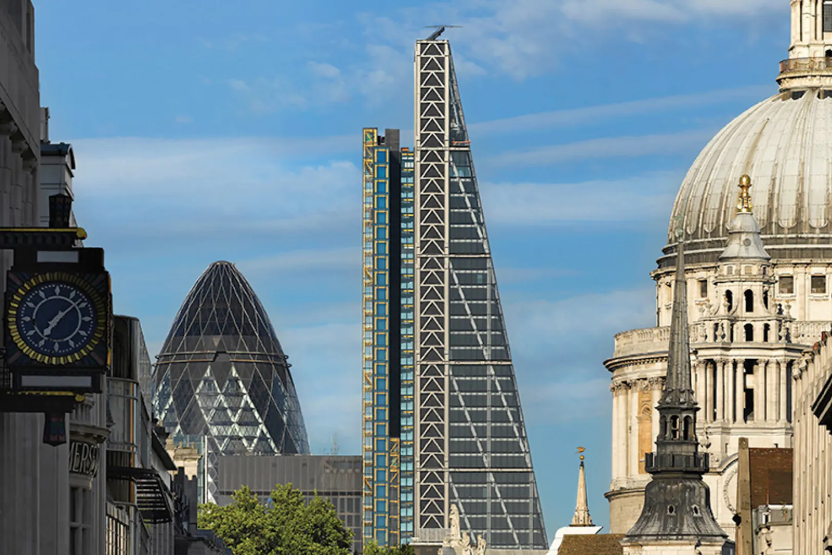Tall triangular building with dome of cathedral in foreground