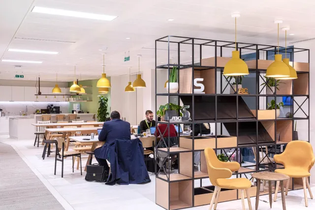People sat at hot desks with a shelving unit in the foreground