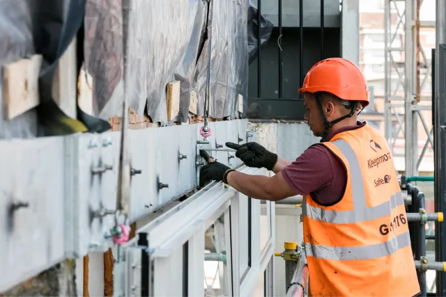 worker dressed in orange working on facade