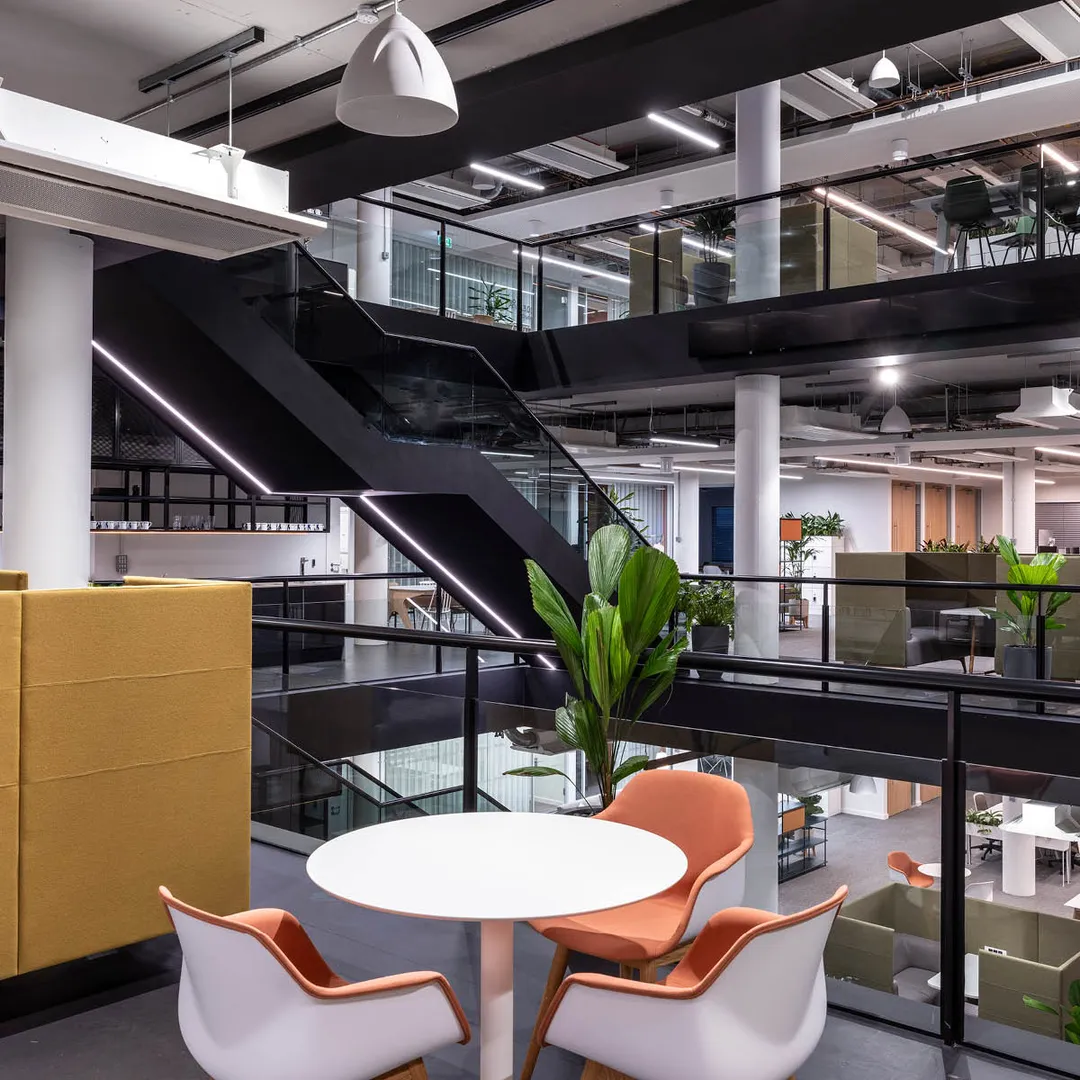 Three orange chairs round a circular table overlooking the atrium