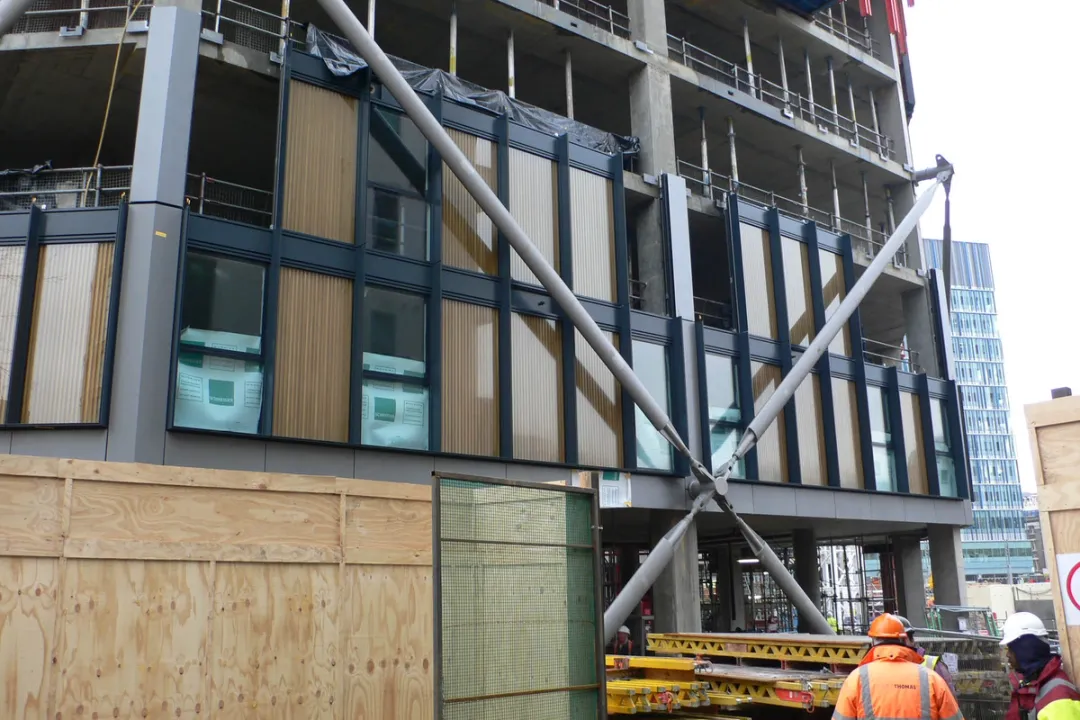 Partially constructed residential tower base with cross bracing over glass panels