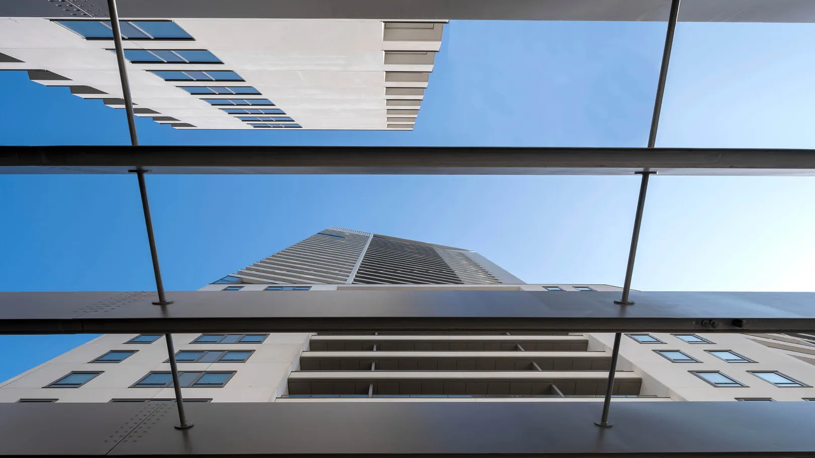 View looking up at two white tower buildings with blue sky in between