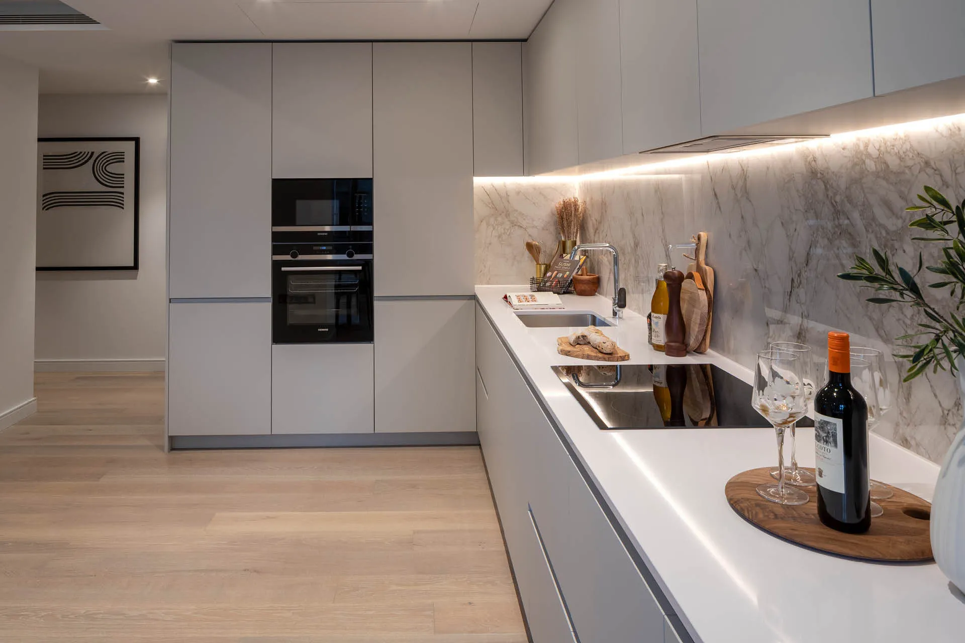 Sleek light grey kitchen cabinets with a white counter a wine