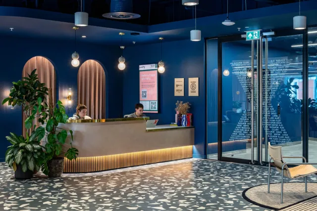 A dark blue reception space with gold desk and plants