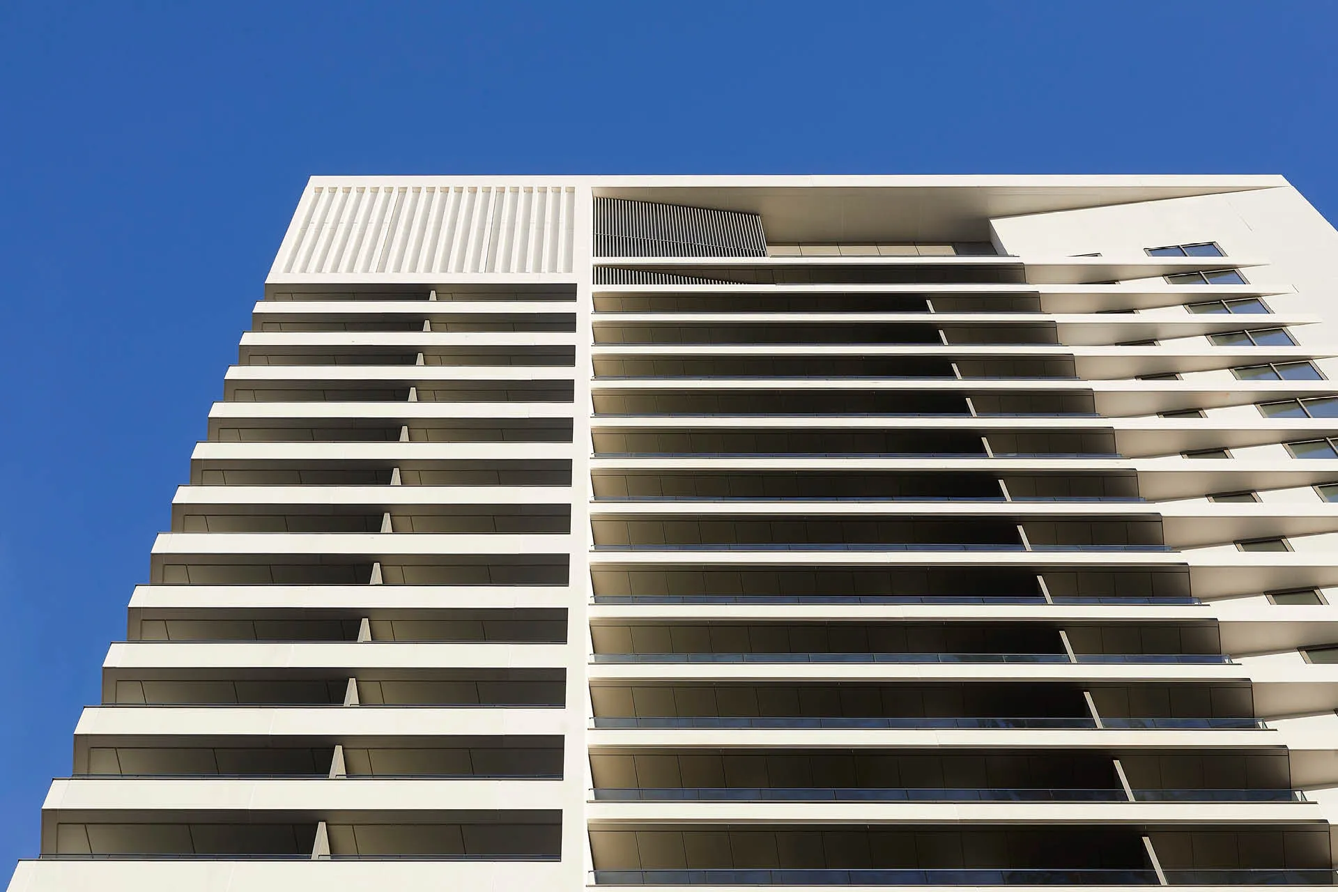 View looking up at white tower with linear balconies