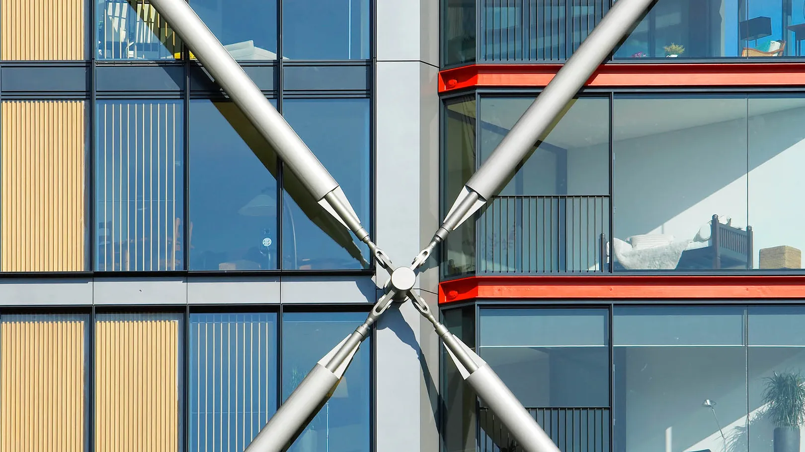 Close up of cross brace on exterior of red and yellow glass residential tower
