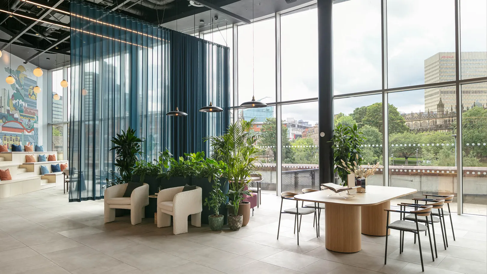 A double height office lobby with chairs and tables overlooking Manchester