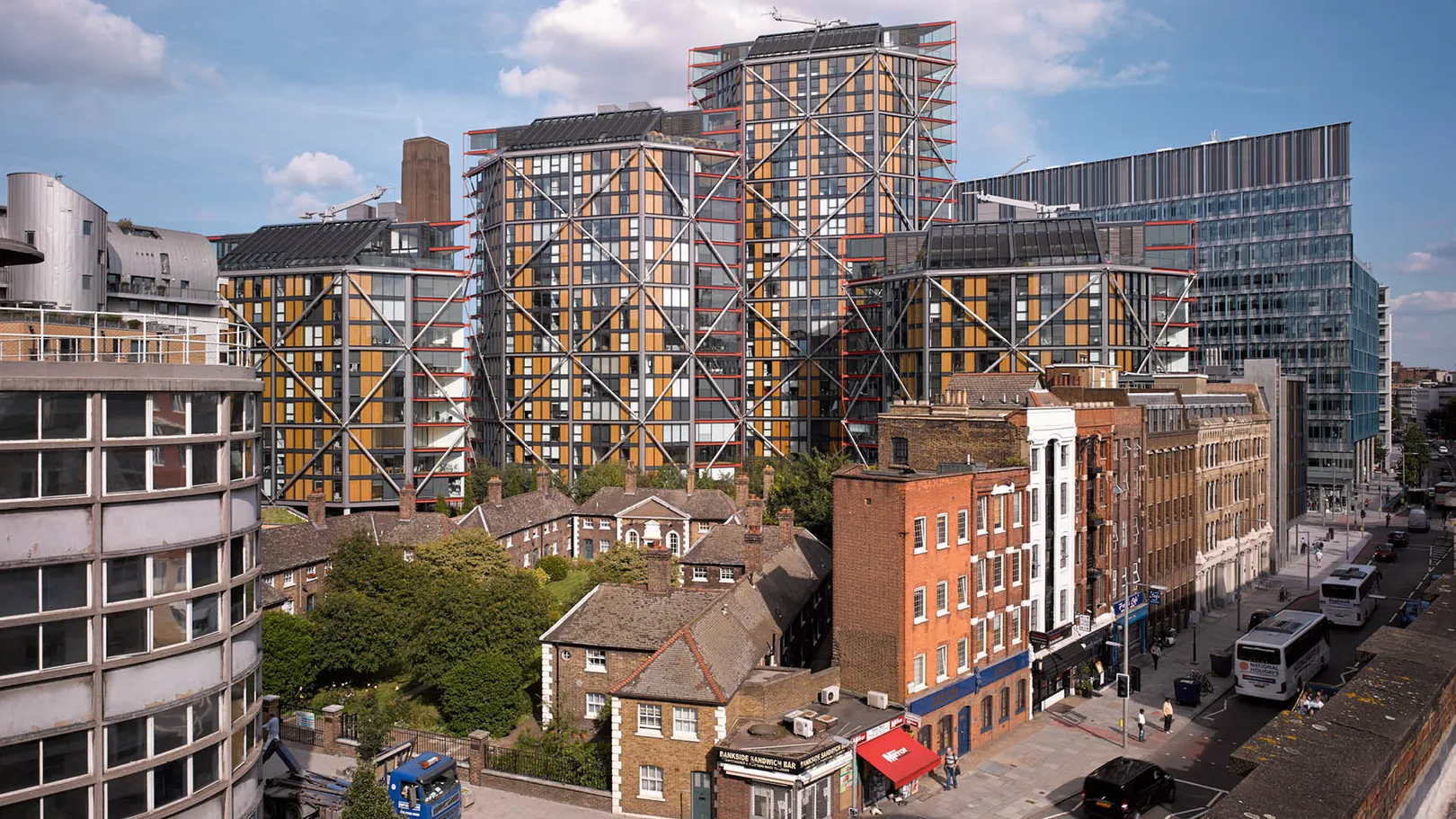 A street view with a cluster of yellow and red glass residential towers in the background