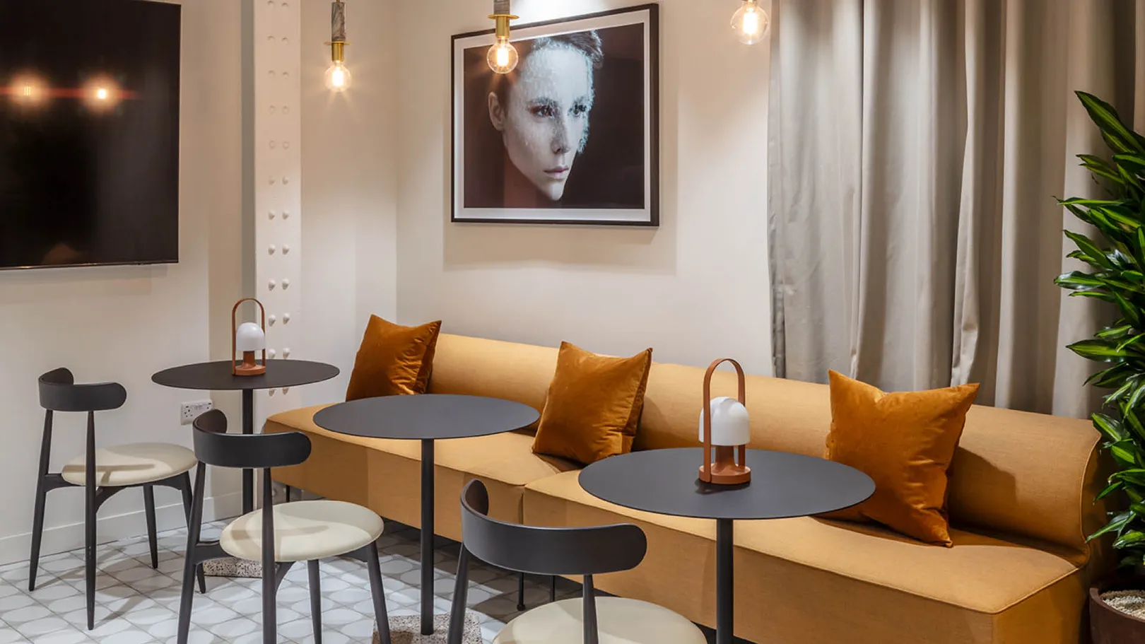 A long orange sofa opposite black tables and chairs 